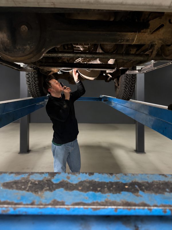 Julien inspecte le dessous d'un véhicule sur pont élévateur